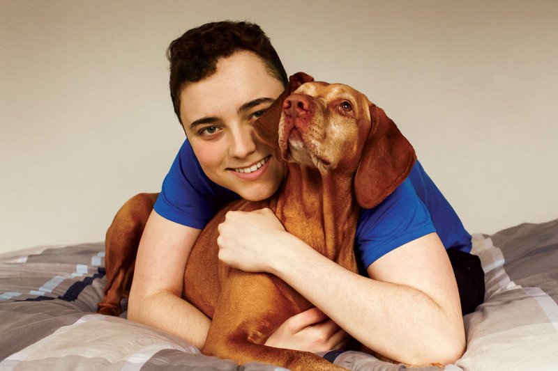 A teenage boy hugs his dog