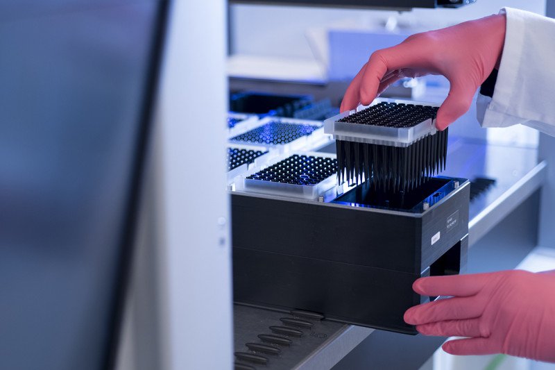 Two gloved hands opening a drawer in a laboratory.