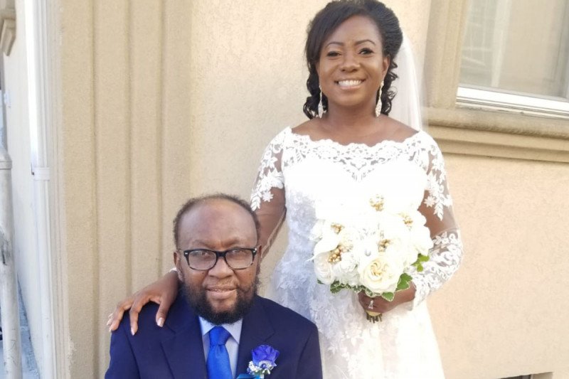 Man seated with his daughter, wearing a wedding gown