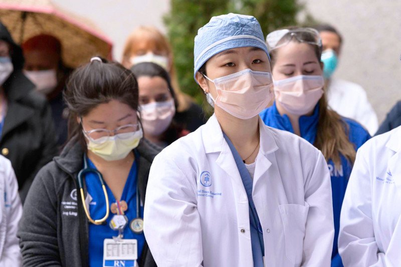 Female doctor wearing a mask and surrounded by her colleagues