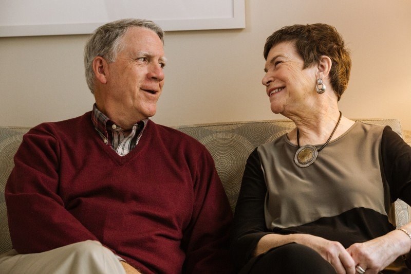 A man and woman sitting on a couch smiling together