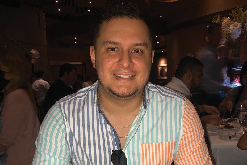 A young man sitting in a restaurant with a slice of cake in front of him