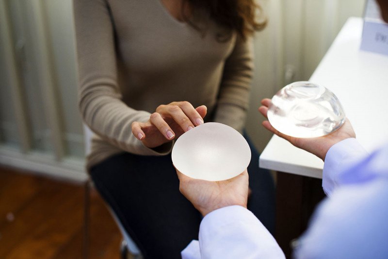 A doctor showing a textured and smooth implant to their patient