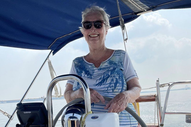 Mary Ann Cornell stands behind the wheel of a boat.