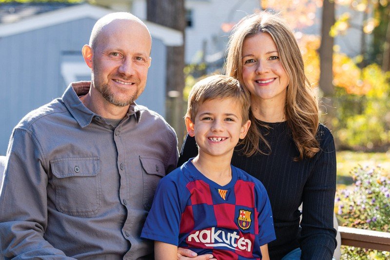 Photo of a man, woman, and child sitting outside smiling