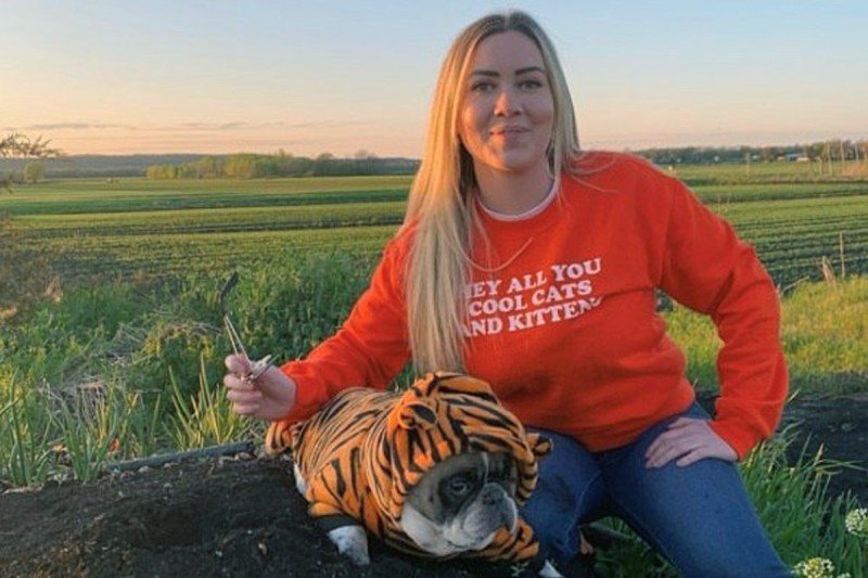 Woman in field with dog dressed as tiger