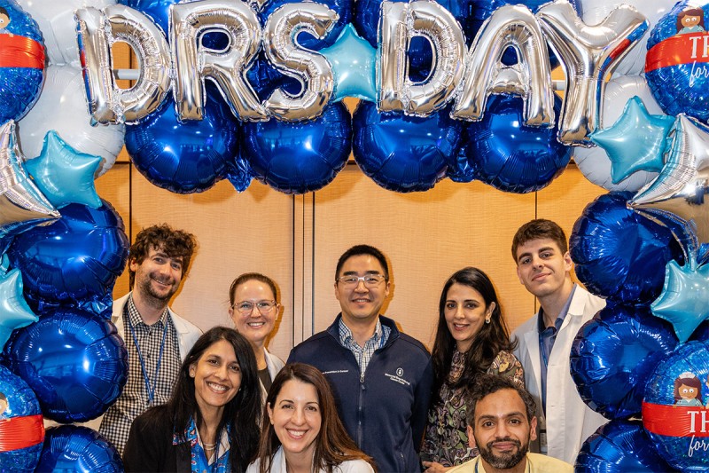  Fellows and faculty celebrating Doctors' Day together beneath a blue and silver balloon display