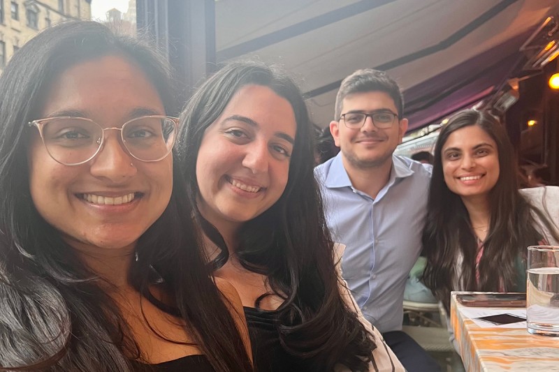 Four MSK fellows, including three women and one man, smile while sitting at a table in a restaurant during a team outing.