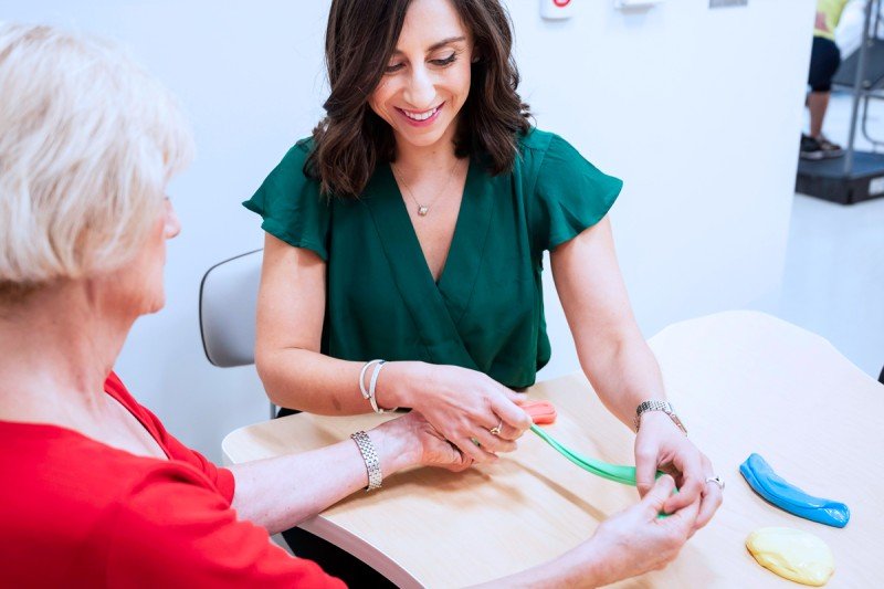 An occupational therapist demonstrates hand exercises with a patient