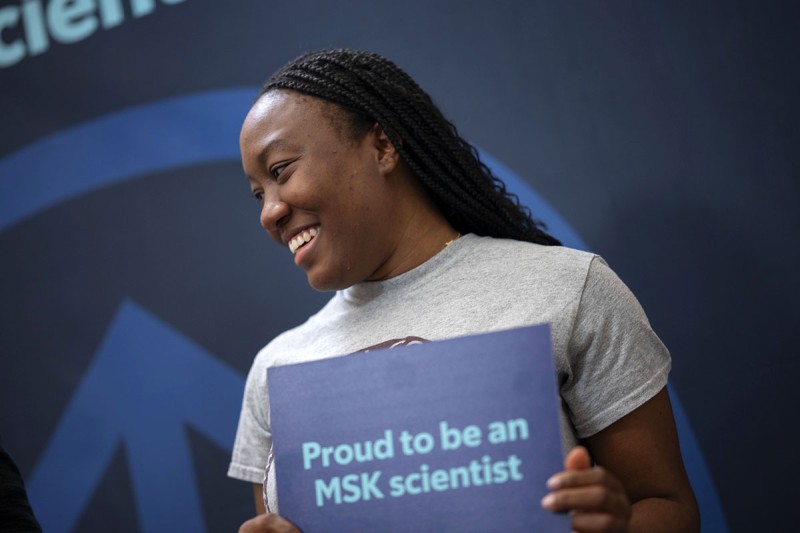 a researcher holds a sign reading "Proud to be an MSK scientist"