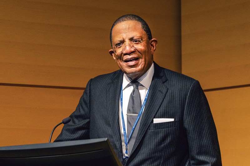 Dr. Selwyn Vickers stands smiling at a podium 
