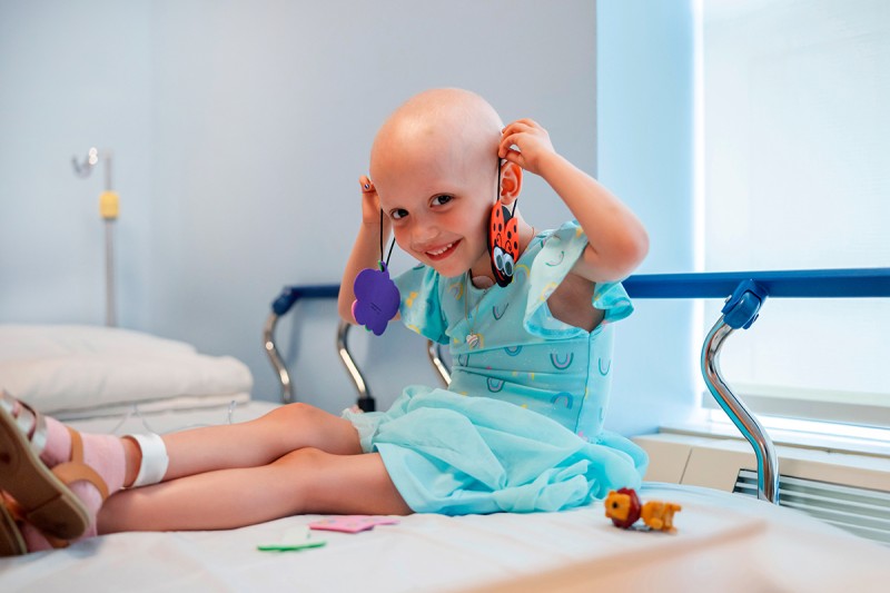 Sienna plays with toys on a hospital bed