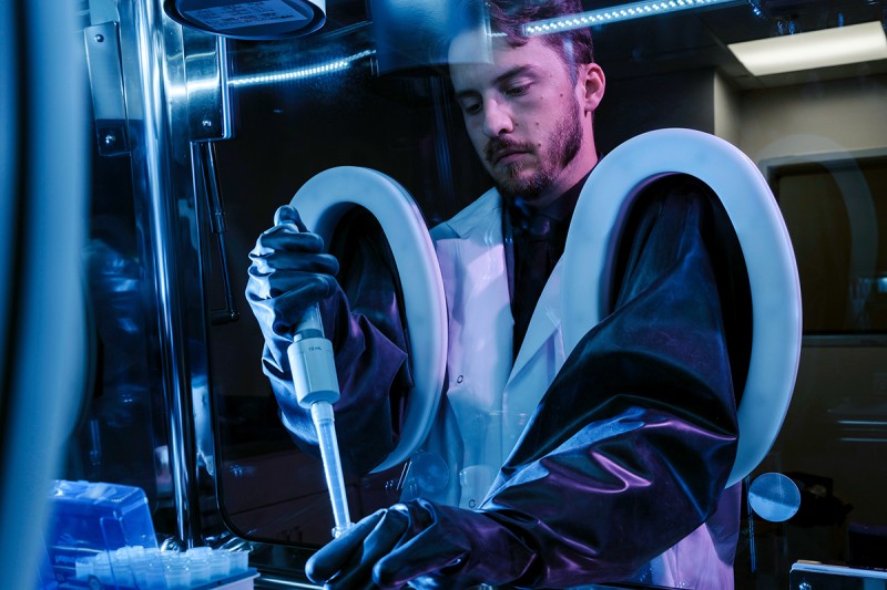 Male scientist wearing protective gear working with radiopharmaceutical materials.