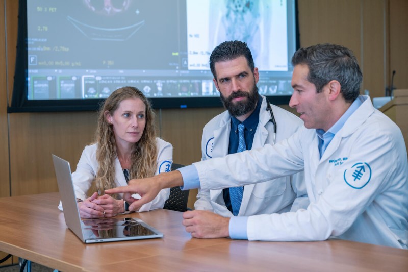Head and Neck Surgeon Benjamin Roman seen talking with MSK colleagues. 