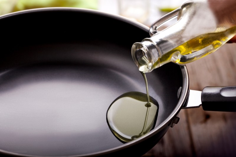 Vegetable oil is poured from a bottle into a frying pan.