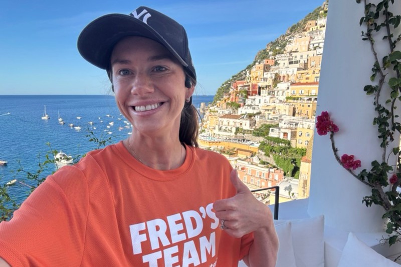 Adrianna Gildner, thyroid cancer patient, wearing orange Fred’s Team shirt, smiling and giving thumbs up in Italy.