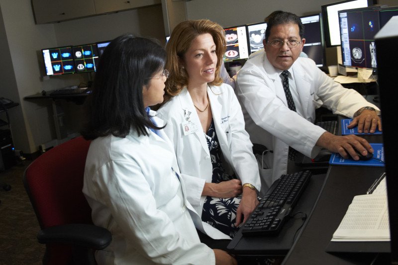 MSK endocrinologist Mabel Ryder, surgeon Vivian Strong, and nuclear medicine doctor Jorge Carrasquillo sit together at a computer reviewing adrenal tumors.