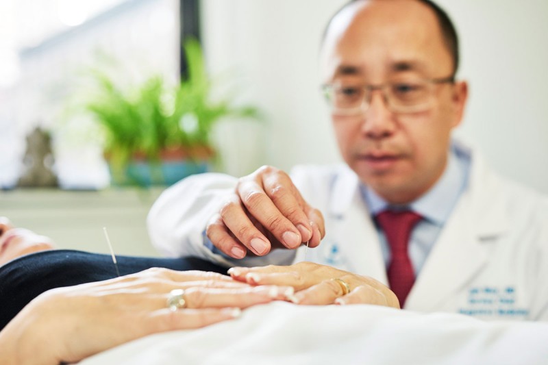 Male physician administering acupuncture to a patient