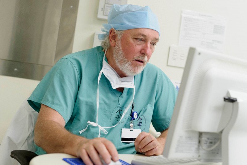 MSK gastric surgeon, Daniel Coit, dressed in his scrubs while working on a computer 