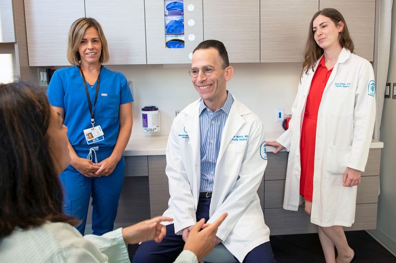 Clinical nurse Jennifer Fox, Evan Matros, MD, and physician assistant Eden Davis meet with a patient.