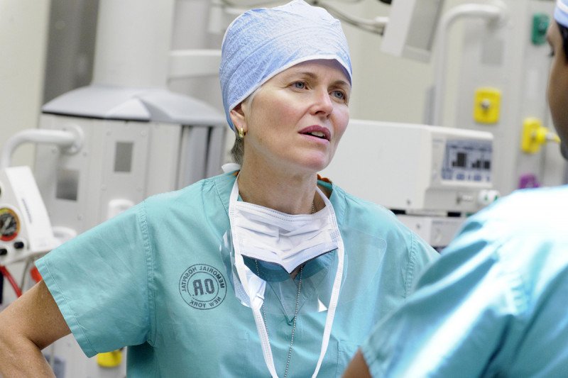 Surgical oncologist Mary Sue Brady speaks to colleague while in surgical scrubs.