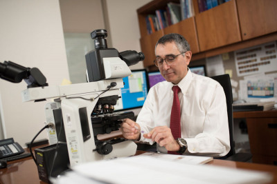 Ahmet Dogan, seated at a microscope, is one of the MSK pathologists who diagnoses lymphoma.