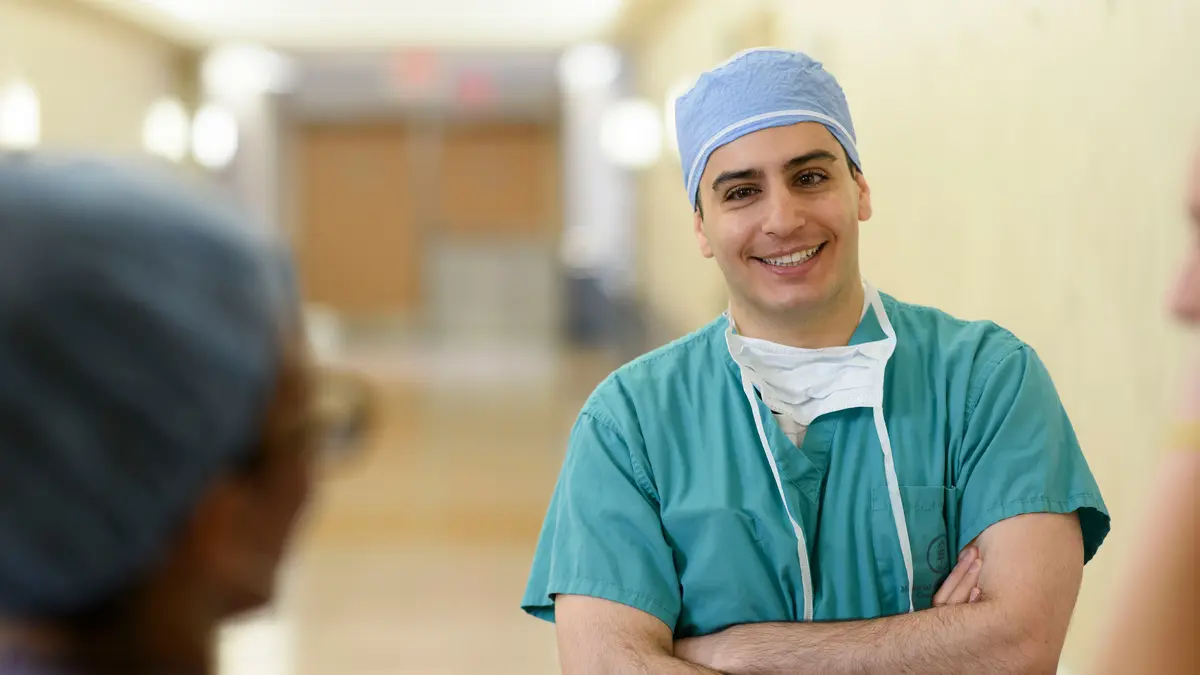 Colorectal surgeon Dr. Emmanouil Pappou, wearing scrubs in a hallway, sees cancer patients in New York City and New Jersey. 