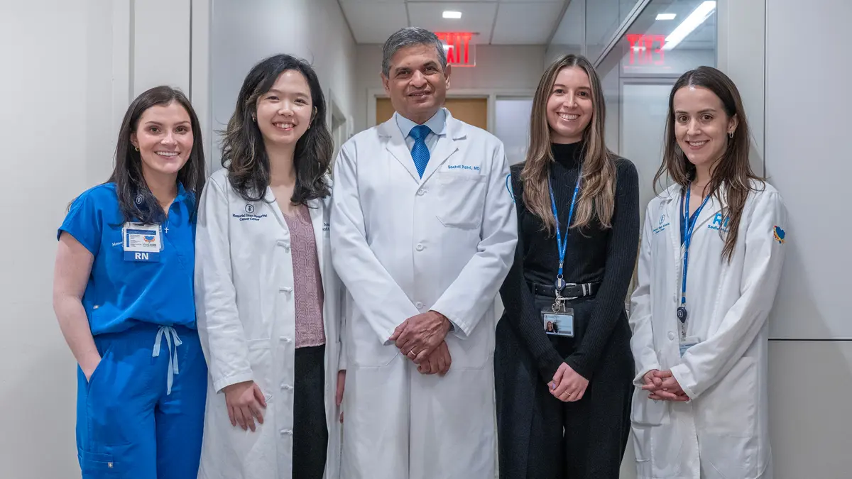 Dr. Patel is standing with 4 women on his clinical care team: 2 registered nurses, a physician assistant, and an office coordinator.  