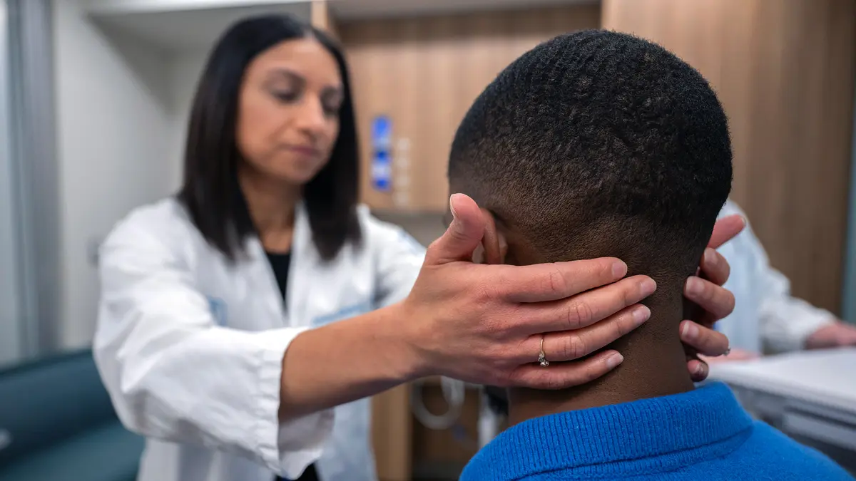 During an exam, Dr. Kriplani faces her patient with her hands on the back of his neck.  