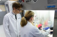 Man and woman in white lab coats looking at test tubes