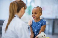 Doctor with back to camera speaking with smiling girl.