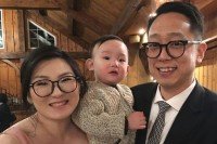 Rev. Paul Yoon holding his infant son and standing with his wife