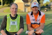 Two men wearing running clothes stand next to each other.