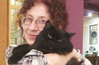 Woman holding long-haired black cat.