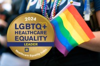 A medal that says 2024 LBGTQ+ Healthcare Equality Leader, over a photo of a person holding a small Pride flag