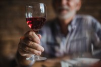 Close-up of hand holding glass of red wine.