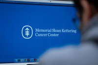 A researcher looks at a computer screen with the MSK logo