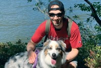 Male AML patient kneeling next to dog outside.