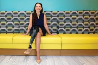 Maddy Ruff sits on a couch, wearing a skirt that displays her prosthetic leg.