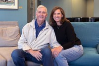 Steve and Sara Harrold smiling and holding hands on a couch in Hope Lodge