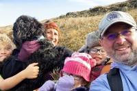 MSK patient Jason Weiner from Alaska takes a selfie with his wife, three kids, and dog off a hiking trail that climbs a hill. 