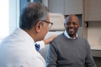 Black male patient smiling and talking to cancer doctor.