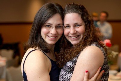 Two sisters hugging and smiling at the camera