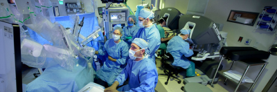 MSK surgeons gathered around a robot used for cancer surgery