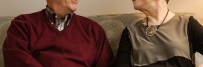 Un hombre y una mujer sentados en un sofá, se sonríen el uno al otro