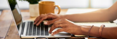 A woman's hands type on a laptop.
