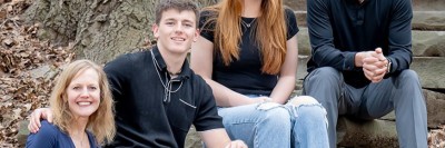 Family of four sitting and smiling for camera.