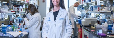 Dr. Mara Sherman in her lab, with two trainees working in the background