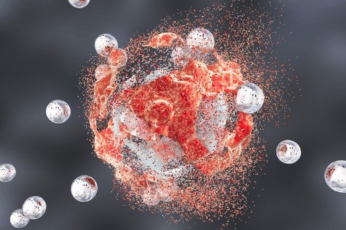 Medical illustration of nanoparticle spheres attacking cancer cell, which is beginning to disintegrate.