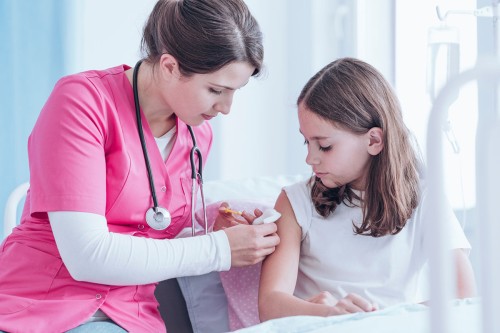 A nurse gives a girl a vaccination.